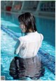 A woman in a white shirt is sitting in a swimming pool.