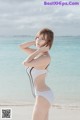 A woman in a white bathing suit standing on a beach.