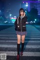 A woman standing on a crosswalk talking on a cell phone.