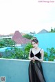 A woman in a black dress standing on a balcony.