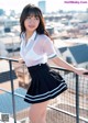 A woman in a white shirt and black skirt posing on a balcony.