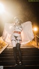 A woman in lingerie and stockings standing on a set of stairs.