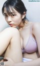 A woman in a purple bra sitting on a bed.